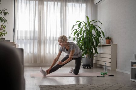 Photo for Active senior woman practicing yoga indoors - Royalty Free Image