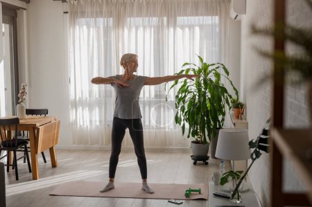 Photo for Active senior woman practicing yoga indoors - Royalty Free Image