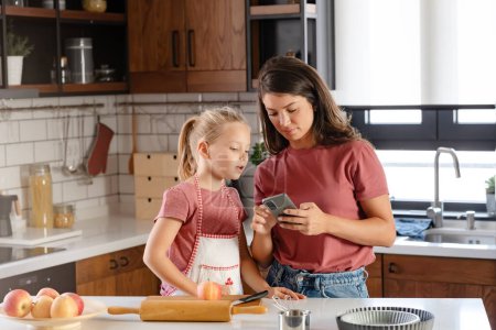 Téléchargez les photos : Belle mère heureuse et sa fille préparant une tarte aux pommes à la maison cuisine. Activités amusantes d'automne en famille - en image libre de droit