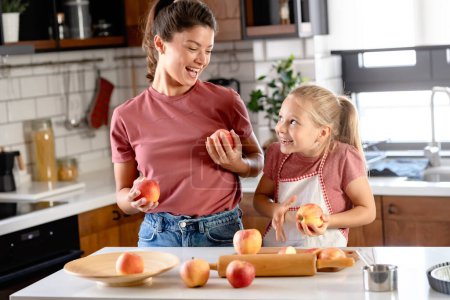Photo for Beautiful mother and daughter posing with apples on the kitchen - Royalty Free Image