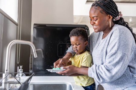 Téléchargez les photos : Jeune femme laver la vaisselle avec son fils - en image libre de droit