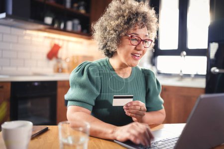 Foto de Mujer mayor que usa el ordenador portátil mientras paga en línea con tarjeta de crédito - Imagen libre de derechos