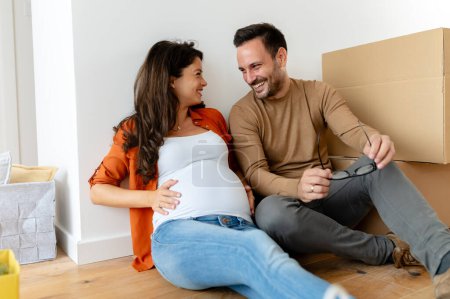 Foto de Joven hermosa pareja hombre y embarazada mujer moviéndose en nuevo apartamento - Imagen libre de derechos