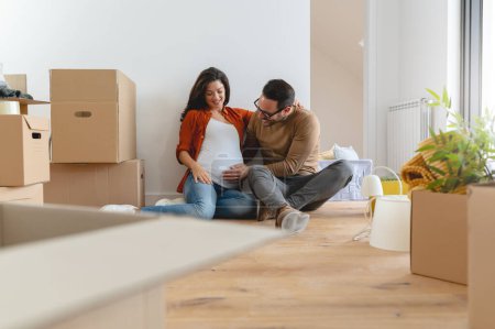 Photo for Young beautiful couple man and pregnant woman moving at new apartment - Royalty Free Image