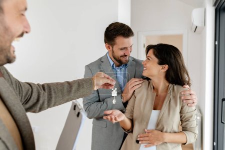 Foto de Hombre y su esposa embarazada, hablando con un agente de bienes raíces visitando apartamento en venta o en alquiler. Futuros padres comprando un apartamento. Concepto inmobiliario - Imagen libre de derechos