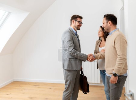Photo for Man and his pregnant wife, talking with a real-estate agent visiting apartment for sale or for rent. Future parents buying an apartment. Real estate concept - Royalty Free Image