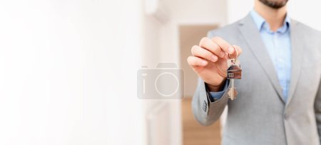 Foto de El agente de bienes raíces tiene una llave de una propiedad. Comprando un apartamento. Concepto inmobiliario e hipotecario. - Imagen libre de derechos