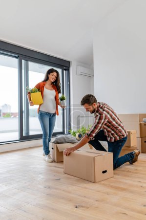 Photo for Young man and woman with boxes at new home - Royalty Free Image