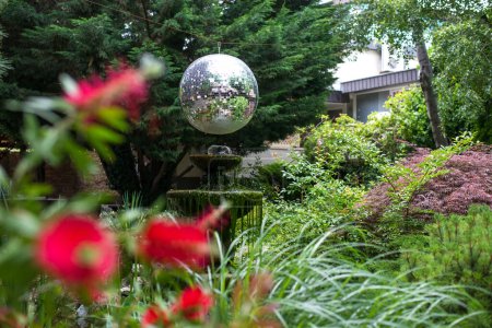 Téléchargez les photos : Jardin extérieur avec fontaine, arbres, buissons, fleurs et boule brillante attrayante. Concentration sélective. - en image libre de droit
