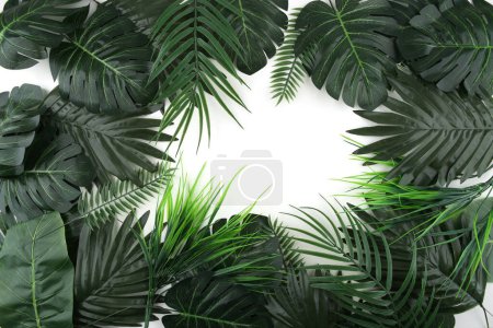 Frame of artificial tropical leaves isolated on white background. Plastic realistic plants with copy space.
