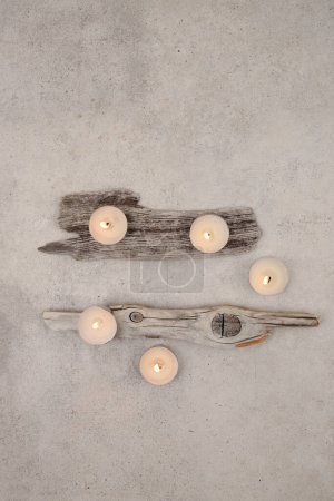 Photo for Sea driftwood pieces and tea light candles on stone background. Pieces of sea drift wood, top view. Bleached dry aged drift wood. - Royalty Free Image
