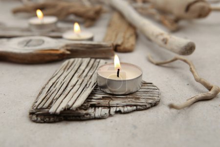 Photo for Sea driftwood pieces and tea light candles on stone background. Pieces of sea drift wood. Bleached dry aged drift wood. - Royalty Free Image