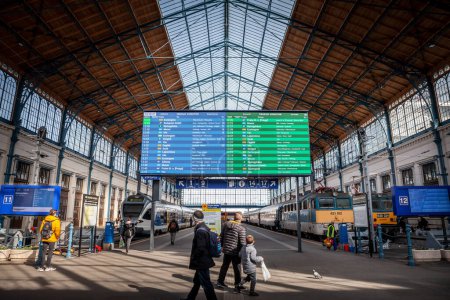 Foto de BUDAPEST, HUNGRÍA - 26 DE FEBRERO DE 2022: plataforma principal de la estación de tren de Budapest Nyugati palyaudvar con un embarque de salidas y pasajeros corriendo - Imagen libre de derechos