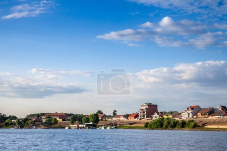 Photo for Panorama of the Reka Sava river with the watefront quay in the left and a few boats passing by in Sremska Mitrovica, a city of Vojvodina, in the srem region, in Serbia. - Royalty Free Image