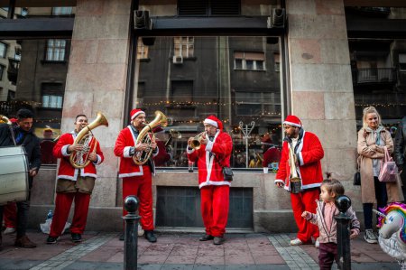 Photo for BELGRADE, SERBIA -JANUARY 1, 2022:  Roma music band dressed as santa claus playing for serbian christmas in the streets of belgrade. These bands are called as well trubaci - Royalty Free Image