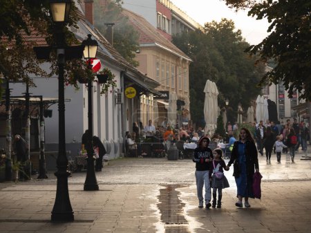 Foto de BELGRADE, SERBIA - SEPTEMBER 24, 2024: Selective blur on a Serbian family, a mother and her kids, walking by the Gospodska ulica street, the main street of Zemun - Imagen libre de derechos