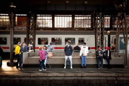 Foto de COLOGNE, GERMANY - NOVEMBER 12, 2022: Selective blur on men wearing a facemask waiting for a train in Koln Hbf Train station during Covid 19 Coronavirus Crisis. - Imagen libre de derechos