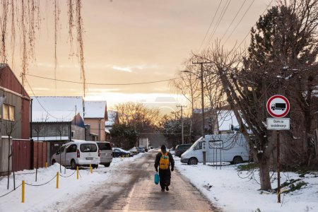 Téléchargez les photos : OMOLJICA, SERBIE - 23 JANVIER 2022 : Flou sélectif sur un homme marchant sur la route et la rue dans le village d'Omoljica, en Voïvodine, Banat, Serbie, à la campagne, pendant un après-midi froid et glacial d'hiver avec beaucoup de neige. - en image libre de droit