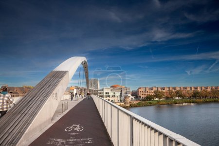Photo for MAASTRICHT, NETHERLANDS - NOVEMBER 10, 2022: Panorama of Maastricht waterfront on Meuse river from the Hogebrug bridge with a focus on pedestrian path and bike lane with bicycles passing by. - Royalty Free Image