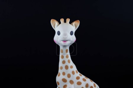 Foto de PARÍS, FRANCIA - 1 DE MARZO DE 2023: Desenfoque selectivo en un primer plano sobre la cabeza de Sophie la jirafa juguete sobre un fondo negro. Sophie la Girafe es una jirafa de caucho hevea, un juguete utilizado para la dentición de bebés, producido en Francia por Vulli. - Imagen libre de derechos