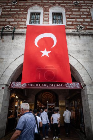 Photo for ISTANBUL, TURKEY - MAY 21, 2022: Entrance to the Spice Egyptian Bazaar of istanbul, crowded, with people entering and a giant turkish flag,. It's a major landmark and market. - Royalty Free Image