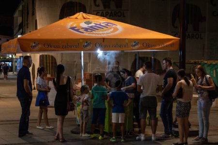 Foto de BRCKO, BOSNIA - 16 DE JULIO DE 2016: Desenfoque selectivo en una multitud de personas, bosnios, esperando comida callejera en un puesto de venta de maíz y otros dulces en el centro de la ciudad de Brcko, en bosnia. - Imagen libre de derechos