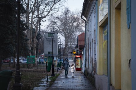 Téléchargez les photos : BAVANISTE, SERBIE - 30 JANVIER 2022 : Flou sélectif sur une famille serbe, mère tenant la main de sa fille, marchant dans un village rural de Voïvodine dans le centre de Bavaniste, à Banat. - en image libre de droit