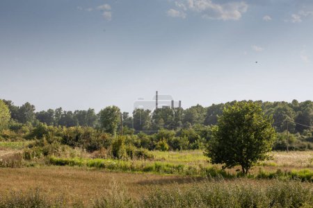 Photo for Nature and serbian countryside fields with the Termoeletrana Kolubara A power station, seen from afar with its chimneys in Veliki Crljeni. It's a coal power plant, main electricity producer in Serbia. - Royalty Free Image