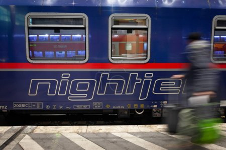 Photo for COLOGNE, GERMANY - NOVEMBER 8, 2022: Selective blur on the Nightjet logo on an overnight train to austria in Koln Hbf with blur of a passenger rushing. NightJet is a train system of Austrian railways. - Royalty Free Image