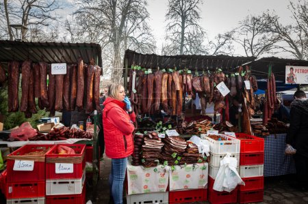 Foto de KACAREVO, SERBIA - 18 DE FEBRERO DE 2023: Stand de un carnicero en el mercado de Slaninijada Kacarevo vendiendo embutidos, carne ahumada y curada, así como cerdo seco, también llamado suvo meso en serbio. - Imagen libre de derechos