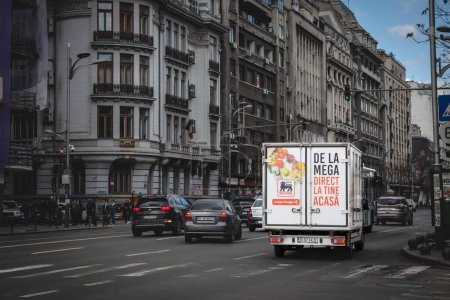 Téléchargez les photos : BUCHAREST, ROUMANIE - 15 MARS 2023 : Logo Mega Image devant un camion de livraison de commandes en ligne à Bucarest. Une partie de Ahold Delhaize, Mega Image est une chaîne roumaine de magasins de détail. - en image libre de droit