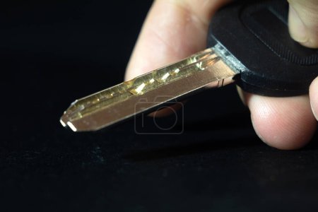 Photo for Selective blur on the dimple pin key held by blurred fingers isolated on a black background. A dimple pin lock and key is a type of safety key and lock used in locksmith environment. - Royalty Free Image