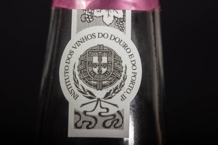 Foto de PORTO, PORTUGAL - 23 DE JUNIO DE 2023: Desenfoque selectivo en la etiqueta de sello y garantía del instituto dos vinhos do douro e do porto en un vino de Oporto, certificando el origen de este vino de Oporto. - Imagen libre de derechos