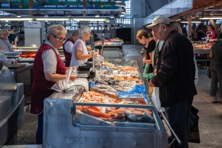 Photo for RIGA, LATVIA - AUGUST 21, 2023: Selective blur on a fishmonger, a fish merchant, selling fish and seafood products to clients at a stall and shop of Centraltirgus, Riga Central market. - Royalty Free Image
