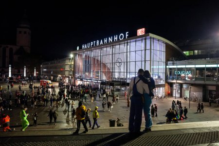 Foto de COLOGNE, ALEMANIA - 6 DE NOVIEMBRE DE 2022: Desenfoque selectivo en un par de besos frente a Koln Hbf, o la estación principal de tren de Colonia (Hauptbahnhof) por la noche. Esta es la principal estación de tren de Colonia. - Imagen libre de derechos
