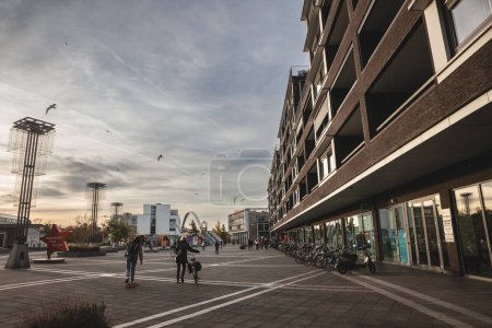 Foto de MAASTRICHT, PAÍSES BAJOS - 9 DE NOVIEMBRE DE 2022: Panorama de Plein 1992 en Maastricht. Es una plaza de Maastricht con edificios residenciales, junto al paseo marítimo de la ciudad, en Limburgo con gente en bicicleta. - Imagen libre de derechos