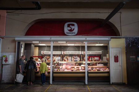 Photo for RIGA, LATVIA - AUGUST 23, 2023: Selective blur on a a group of clients buying meat at a butcher stall and shop of Centraltirgus, Riga Central market. - Royalty Free Image