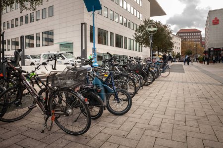 Foto de DORTMUND, ALEMANIA - 5 DE NOVIEMBRE DE 2022: Desenfoque selectivo en bicicletas, estacionado en un aparcamiento para bicicletas, en el centro de la ciudad de Dortmund, junto a una calle peatonal. El ciclismo y las bicicletas son ampliamente utilizados en Alemania. - Imagen libre de derechos