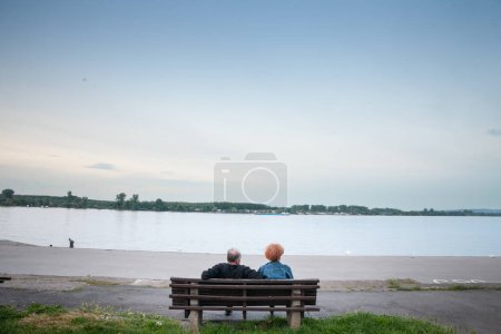 Photo for BELGRADE, SERBIA - MAY 15, 2023: Selective blur on a senior old couple, man and woman serb, sitting together on a bench looking at the danube river in Zemun, a suburb of Belgrade. - Royalty Free Image