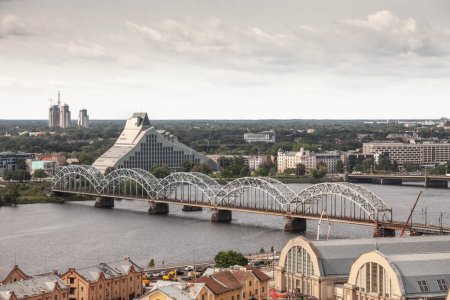 Photo for Daugava river in Riga, latvia, from above with dzelzcela tilts or Riga Railway Bridge with a skyline of business skyscrapers in background with high rise towers and Centraltirgus riga central market. - Royalty Free Image