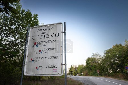 Téléchargez les photos : KUTJEVO, CROATIE - 15 SEPTEMBRE 2023 : Panneau indiquant en trois langues la sortie et le départ de Kutjevo sur une route asphaltée au crépuscule. Kutjevo est un village croate de Slavonie, sur les monts Papuk.. - en image libre de droit