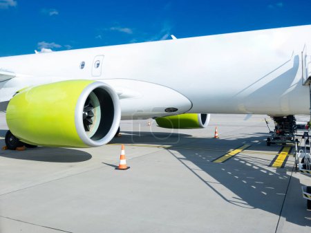 Vibrant cargo plane parked on a European tarmac, its prominent engine and striking lime accents highlighting the robust logistics and air freight transport sector, essential for global trade and commerce.
