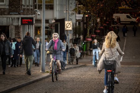 Photo for MAASTRICHT, NETHERLANDS - NOVEMBER 10, 2022: Selective blur on People biking in Maastricht city center with focus on senior old woman. Netherlands are known for people using bicycle as transportation. - Royalty Free Image