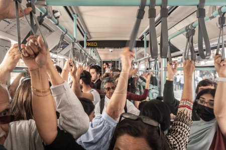 Téléchargez les photos : ISTANBUL, TURQUIE - 19 MAI 2022 : Une foule de Turcs tenant des sangles et des rails dans un tram d'istabul pendant les heures de pointe, avec une circulation dense dans les transports en commun. - en image libre de droit