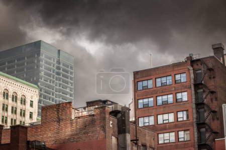 Panorama of Old brick buildings, American architecure, and modern business glass skyscrapers standing in downtown Montreal, the biggest economic hub of Quebec, with a cloudy sky.