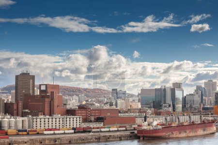 Foto de Panorama de Montreal con un buque de carga en el puerto industrial de Montreal, Quebec, con el horizonte y el distrito de negocios del centro con sus rascacielos de gran altura detrás. - Imagen libre de derechos