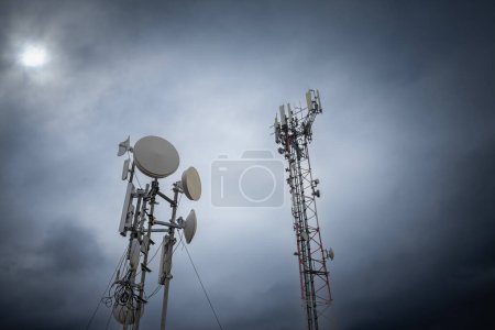 Mobilfunk-Basisstation, ausgestattet mit 3G-, 4G- und 5G-Antenne, an der Spitze eines europäischen Gebäudes in Ungarn mit dunklen Wolken bei schlechtem Wetter, die für die Netzabdeckung, den Empfang und die Übertragung von Mobiltelefonen verwendet werden.