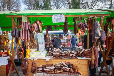 Photo for KACAREVO, SERBIA - FEBRUARY 18, 2024: Stand of a butcher in the Slaninijada Kacarevo market selling sausages, smoked and cured meat, as well as dried pork, also called suvo meso in Serbian. - Royalty Free Image