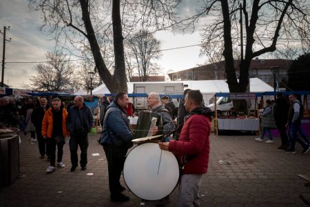 Téléchargez les photos : KACAREVO, SERBIE - 21 FÉVRIER 2024 : Trubaci, groupe de musique roma traditionnelle, jouant dans les rues musique balkane traditionnelle, batterie et accordéon, dans le slaninijada de Kacarevo, au crépuscule. - en image libre de droit