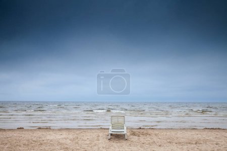 Panorama de una silla de plástico vacía en la playa de Jurmala (Jurmalas Pludmale) en Dubulti, Letonia, en el mar Báltico, en una tarde nublada lluviosa. Jurmala es un balneario de Letonia en estados bálticos.